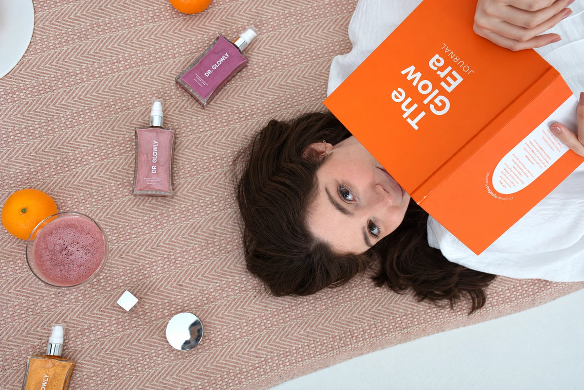 Fotografía editorial con una modelo, el diario Glow Era y un shimmer violeta Dr. Glowly sobre el tejido.